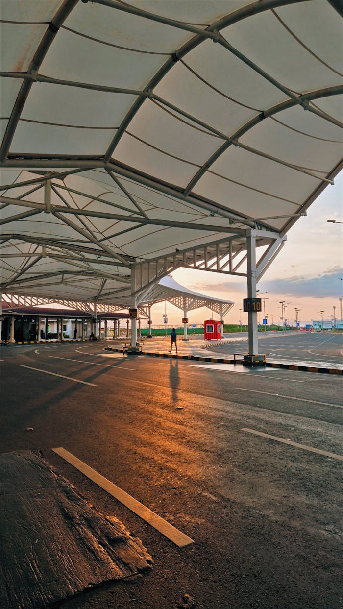 A sunset view of a modern architectural walkway with a lone figure casting a long shadow.