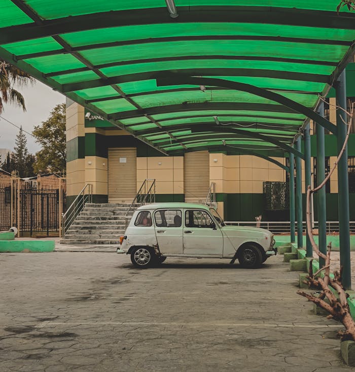 car parked under a modern green roof structure, outdoors.